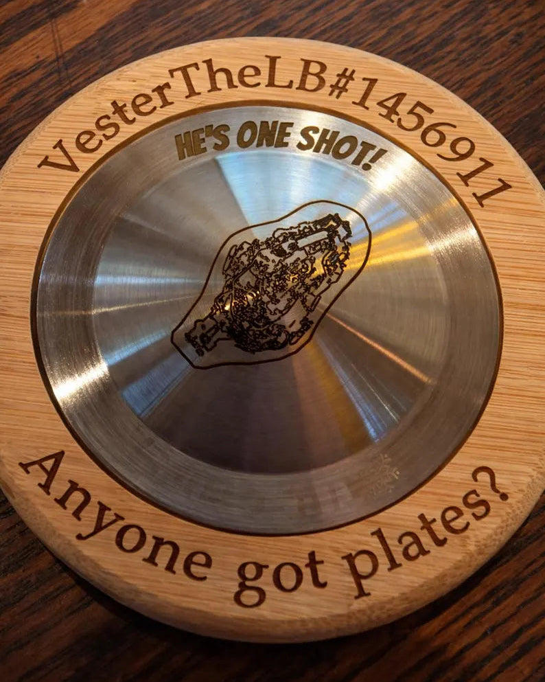 Metallic disc with engraved text and design on a wooden surface